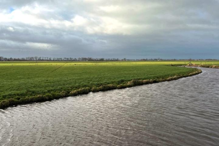 Foto van een kraan die bezig is met het omkeren van de toplaag, de zandlaag en de veenlaag